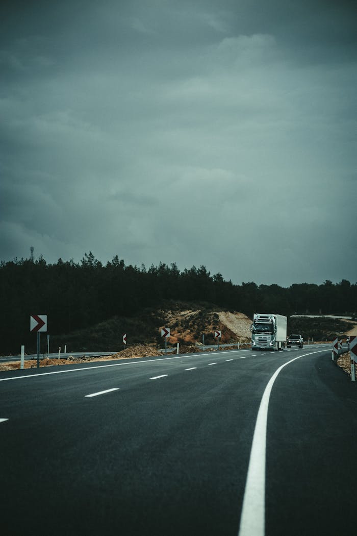 A solitary truck travels on a winding highway under a cloudy sky, embodying a sense of solitude and journey.